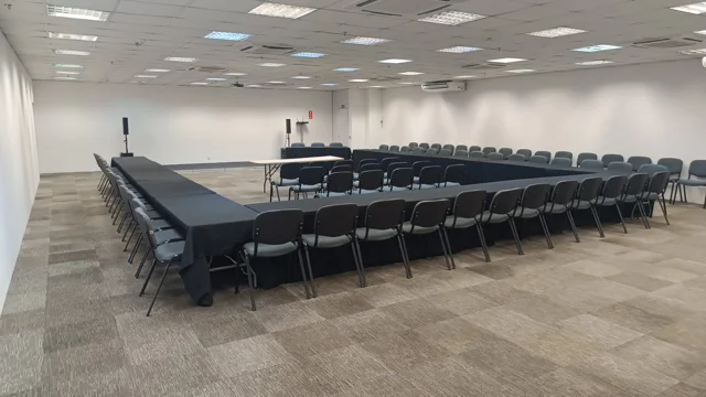 Salão com mesas e cadeiras organizadas em formato de reunião